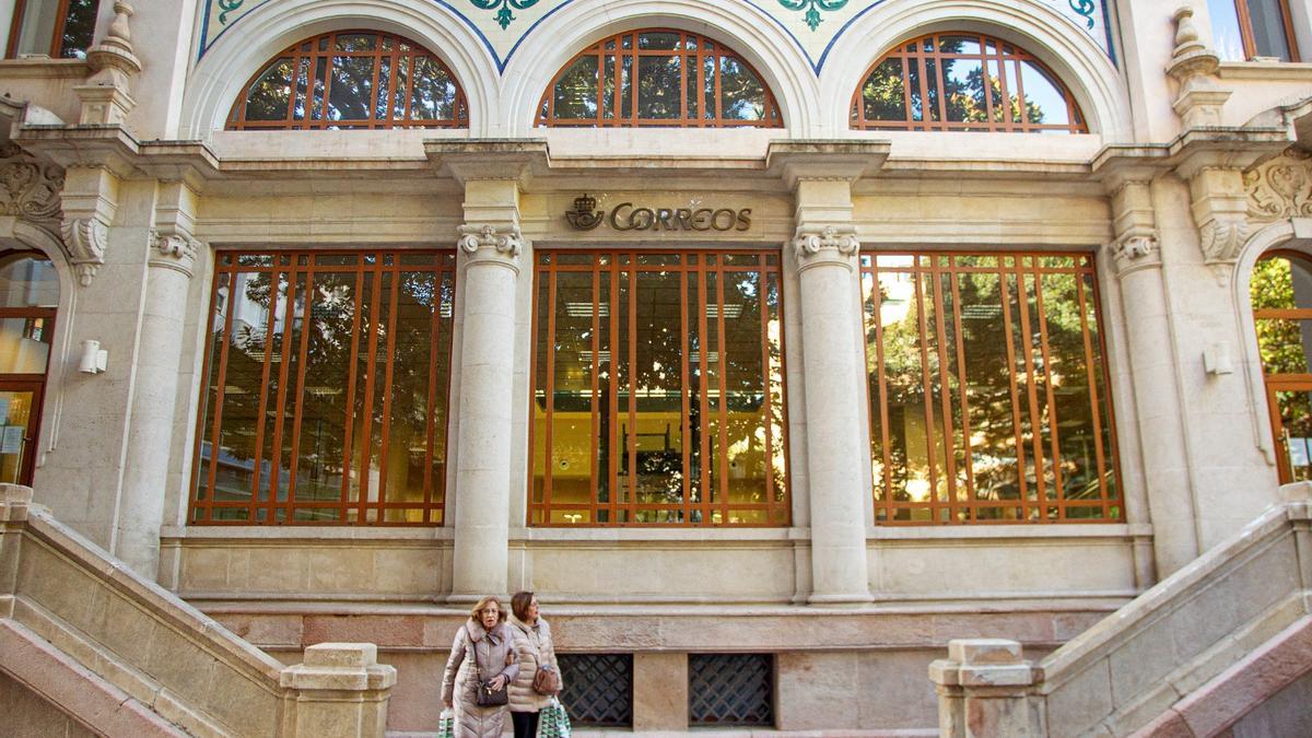 Dos mujeres salen del edificio de Correos en Alicante, minutos antes del cierre.