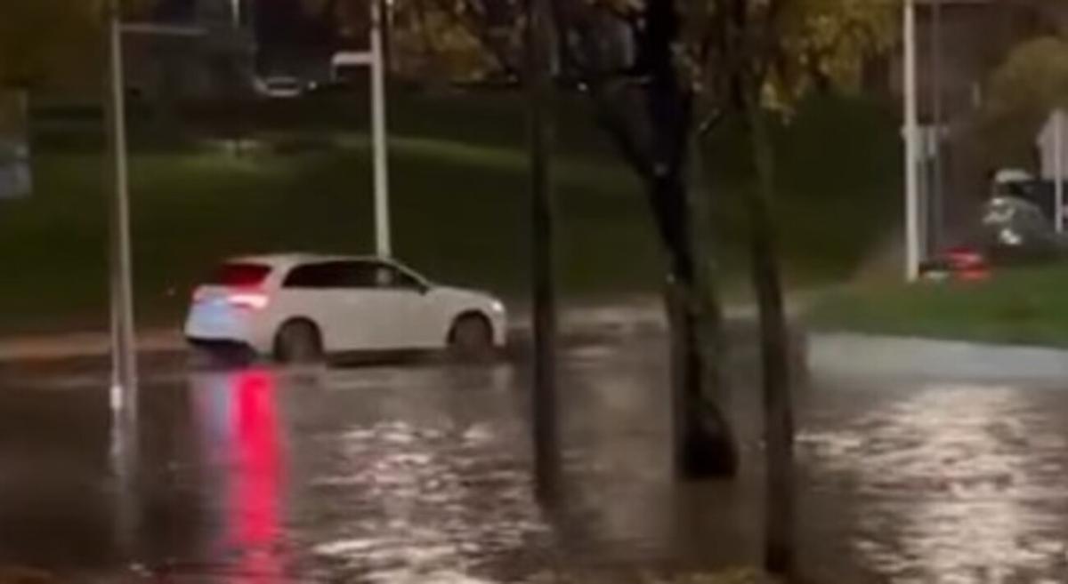 Varios coches pasan por la rotonda do Vieiro durante la tromba de agua de este jueves