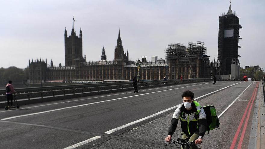 Un repartidor en bicicleta pasa por el puente de Westminster en Londres.