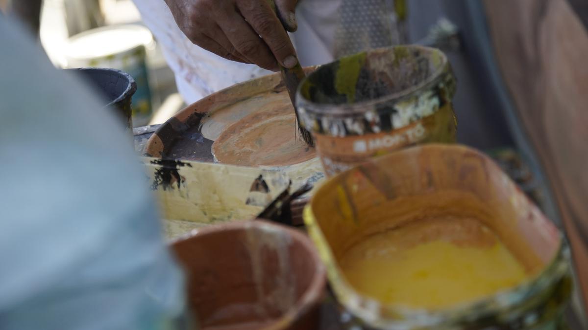 Un trabajador manipula botes de pintura.