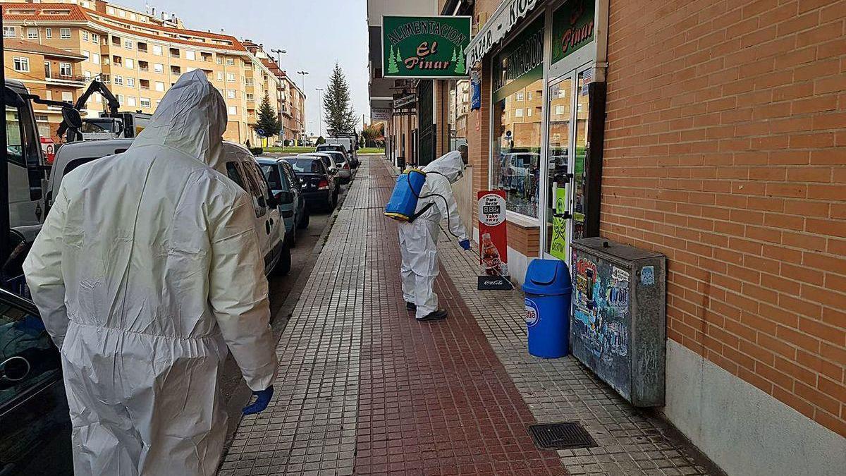Dos trabajadores municipales desinfectan una acera en la avenida Luis Morán durante el decreto de alarma.