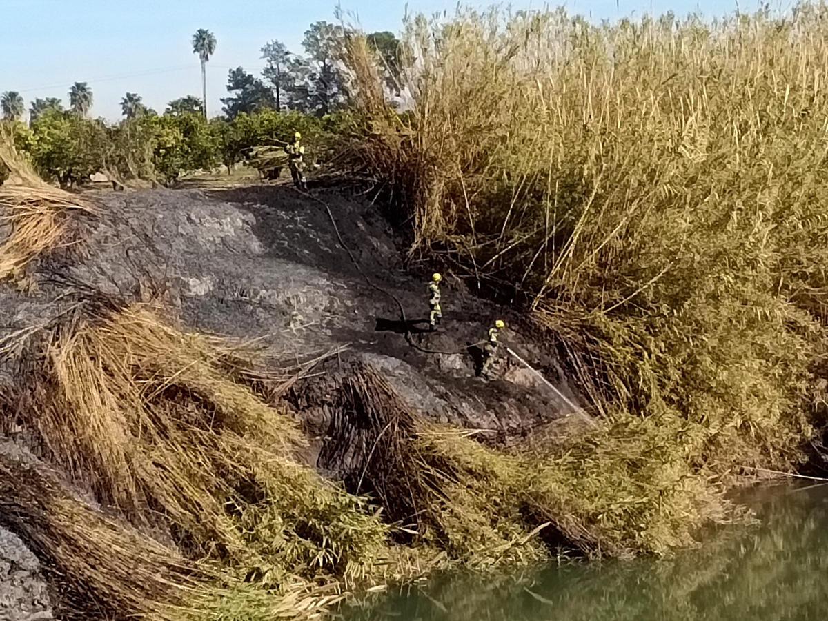 Una brigada forestal, esta mañana, en la orilla del río afectada por el fuego.