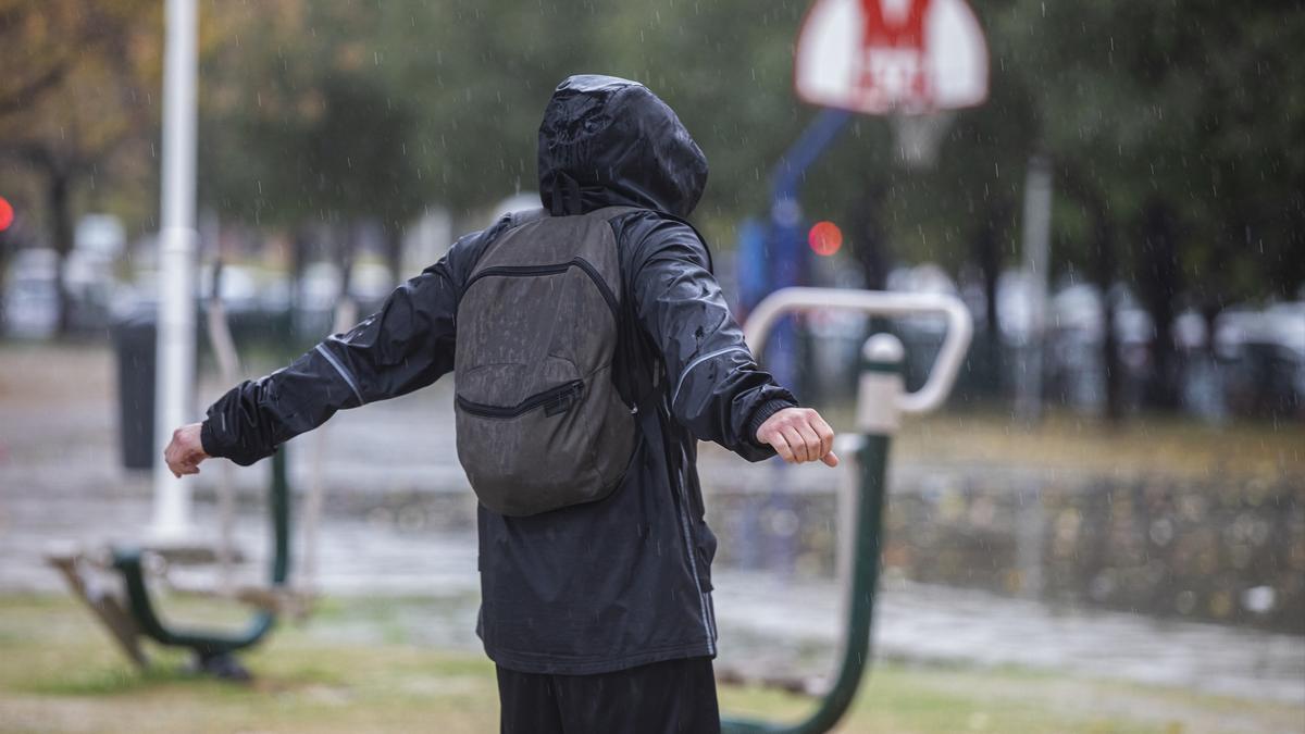 Una persona con un chubasquero bajo la lluvia en una imagen de archivo.