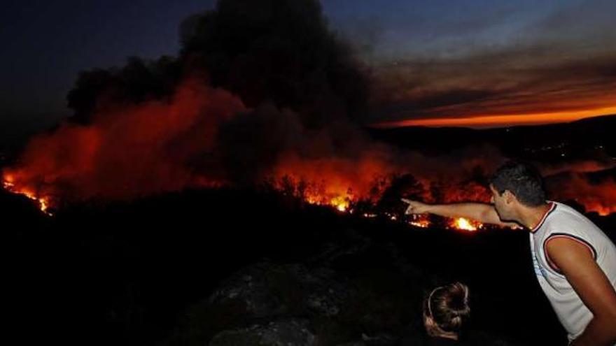 Vecinos observan el avance del incendio que se declaró ayer en el municipio de Oia.  // José Lores