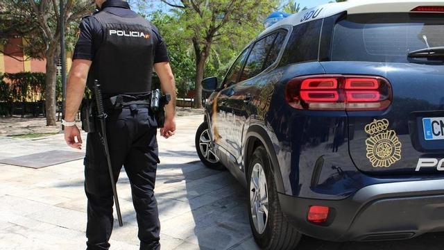 Foto d’arxiu d’un agent de la Policia Nacional de València al costat del seu cotxe patrulla.