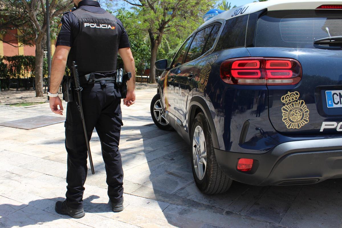 Foto de archivo de un agente de la Policía Nacional de València junto a su coche patrulla.