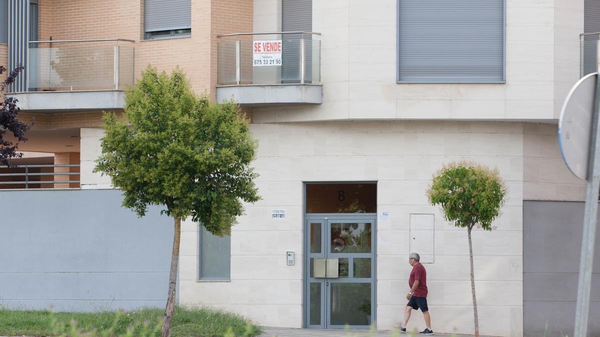 Un hombre pasando por delante de una vivienda en venta