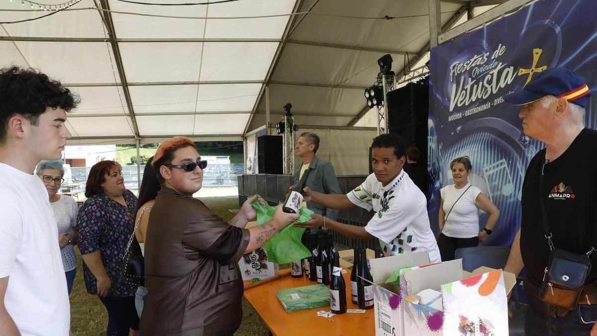 Raul Jaquez entregando la bolsa con el bollo y una botella de vino a Fernando Alonso, vecino del barrio