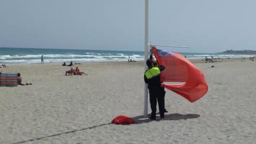 Un agente coloca la bandera roja en la playa de San Juan por medusas.