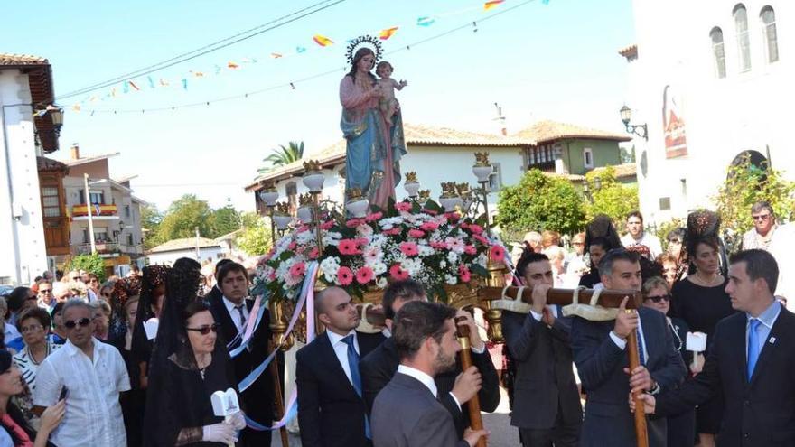 Sobre estas líneas, la Virgen a hombros de los mozos y acompañada por las damas de mantilla. A la izquierda, uno de los ramos en plena procesión.