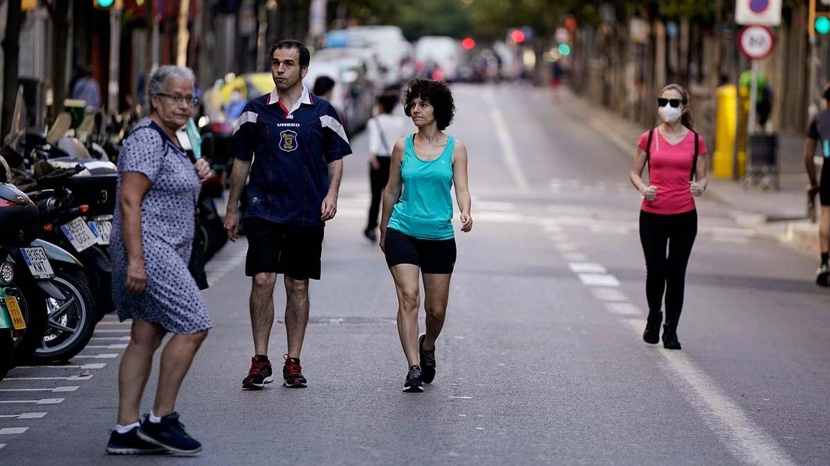 Peatones caminan y practican deporte en la Via Laietana de Barcelona, cerrada al tráfico. En la foto, la calle de Gran de Gràcia, también sin coches.