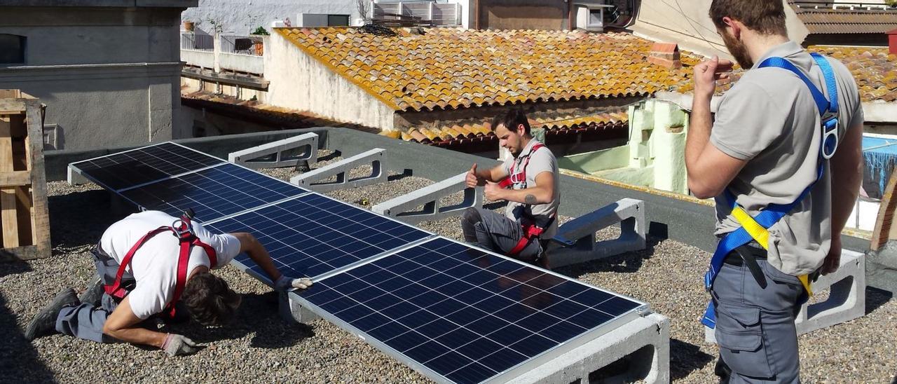 Uns operaris instal·len plaques en una teulada | DIARI DE GIRONA