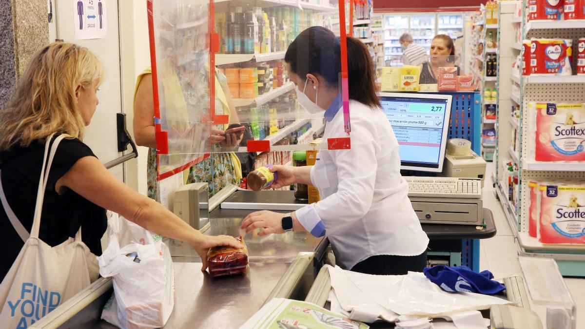 Una cajera atienda a una clienta en un supermercado gallego.