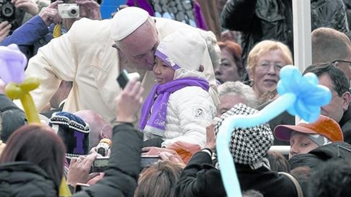 Bergoglio besa a un niño desde el papamóvil, en la plaza de San Pedro del Vaticano, esta semana.