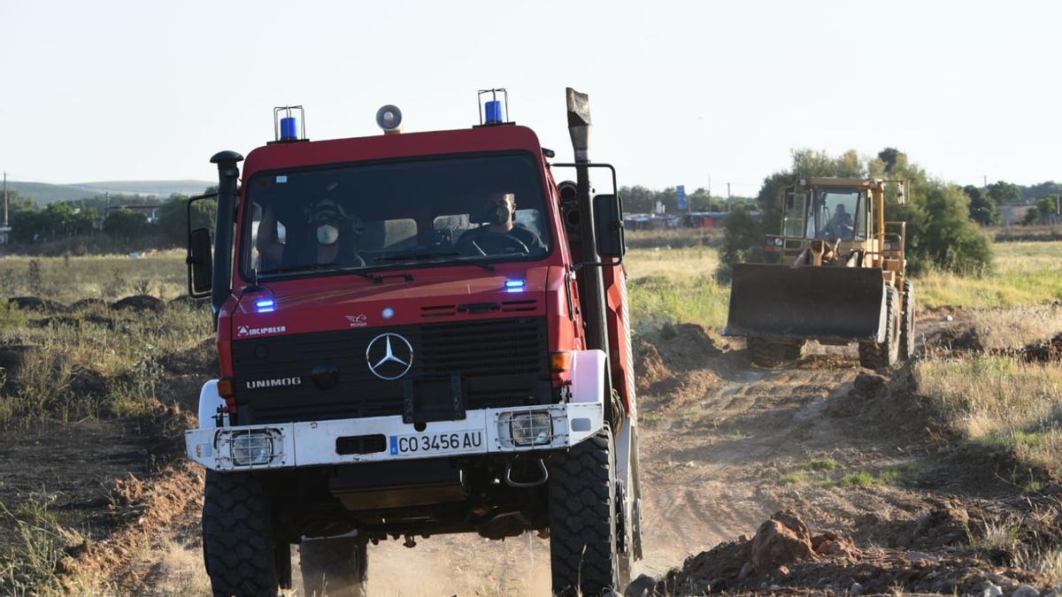 Una excavadora, tras el vehículo de los bomberos, ha sido empleada para hacer un cortafuegos que evitase que el fuego alcanzase las viviendas.