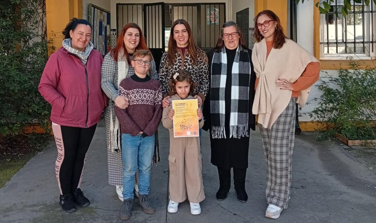 Lorena García, segunda por la izquierda, junto a dos de sus hijos, y representantes del colegio Andalucía, con el cartel de la carrera.