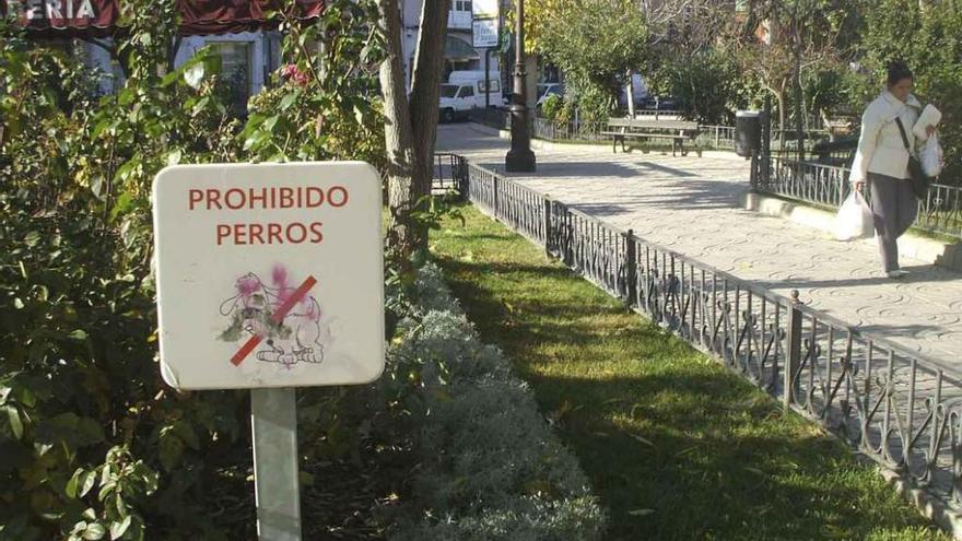 En primer término, cartel que prohíbe el paso de perros a uno de los jardines de la ciudad. Foto