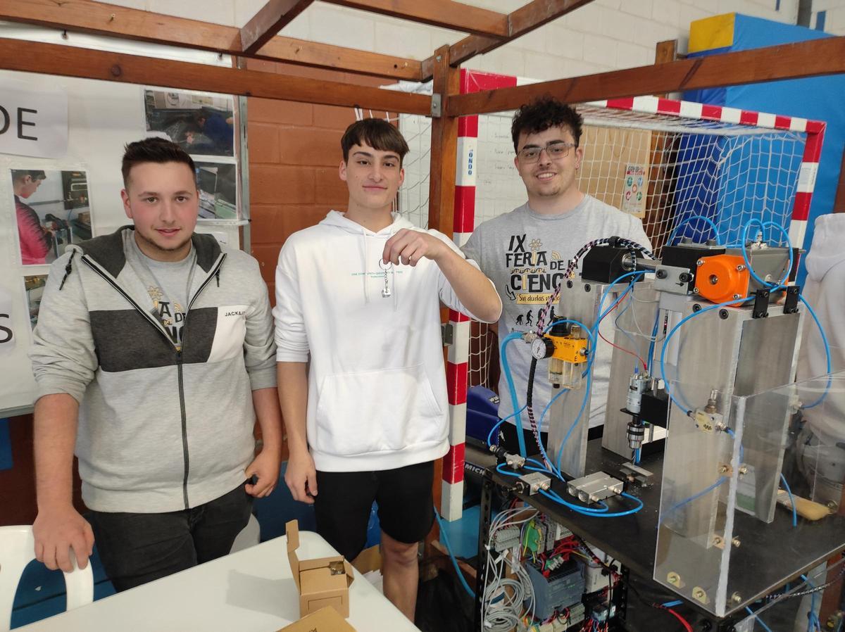 Ángel García, Javi Fernández y Diego García con la máquina que fabrica llaveros.