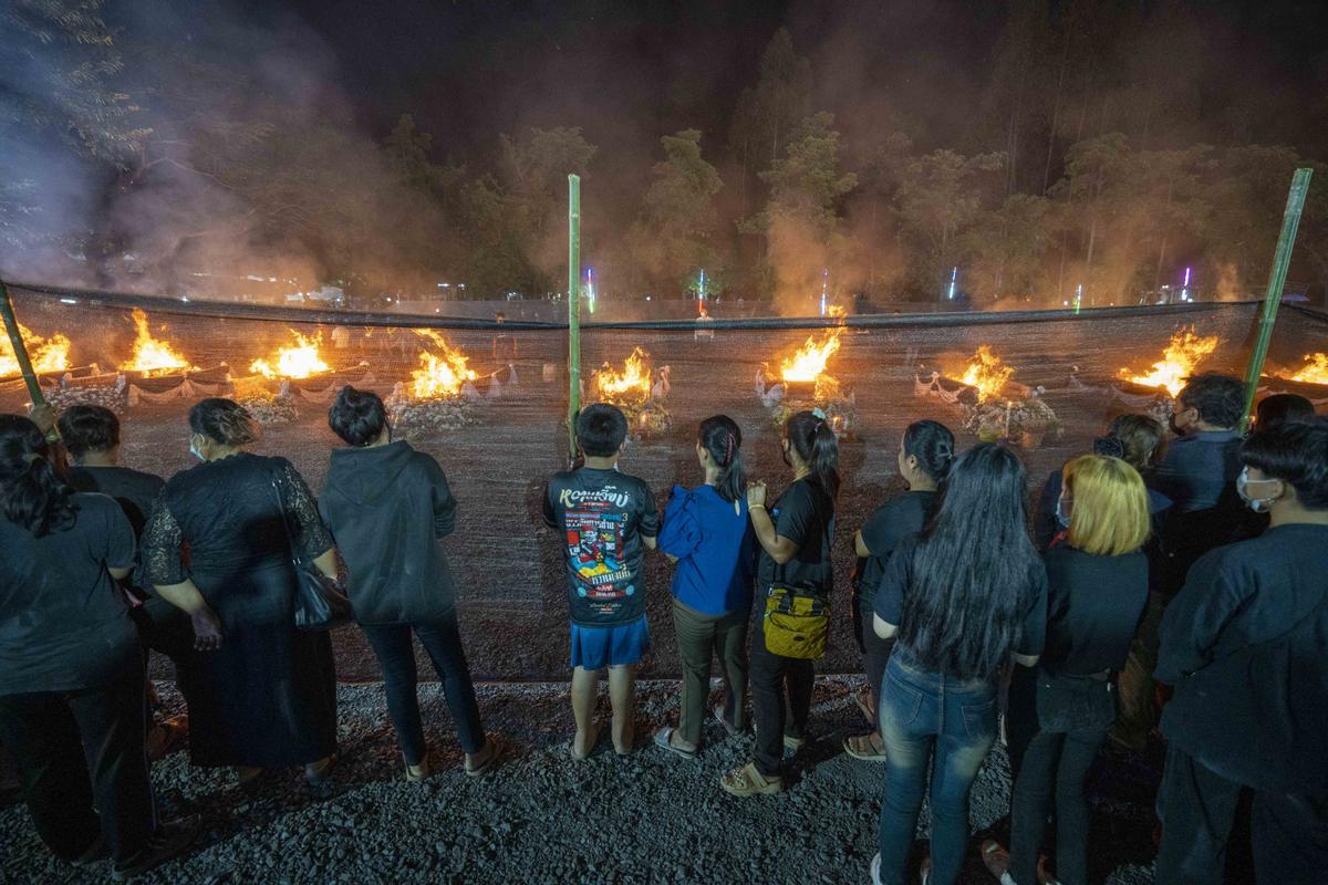 La gente observa cómo las piras funerarias incineran a 19 víctimas del tiroteo en la guardería de Uthai Suwan en el templo Wat Rat Samakee en Uthai Sawan. Un exoficial de policía disparó y mató a 37 personas, al menos 24 de ellos niños, después de irrumpir en una guardería infantil en el noreste de Tailandia.