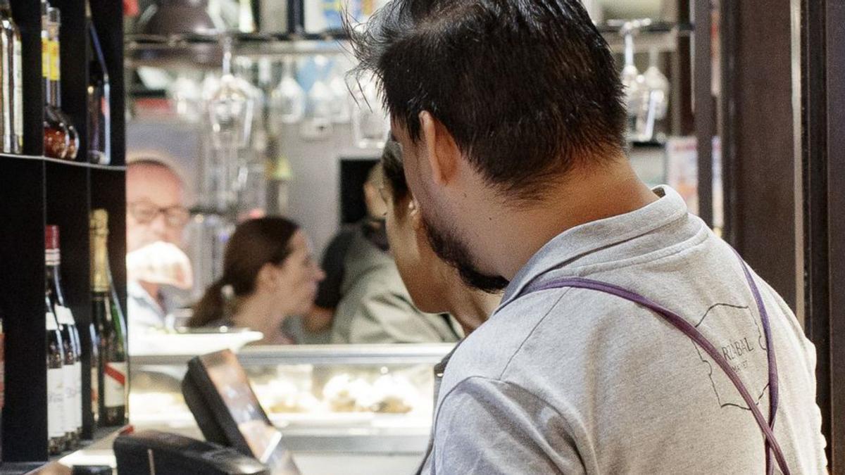 Dos camareros cobran las cuentas de los clientes en un bar. | E. P. (ARCHIVO)