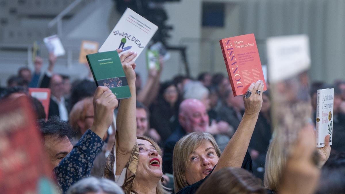 Asistentes a la gala de los premios de la 75a Nit de les Lletres Catalanes levantan los libros que recomendarían