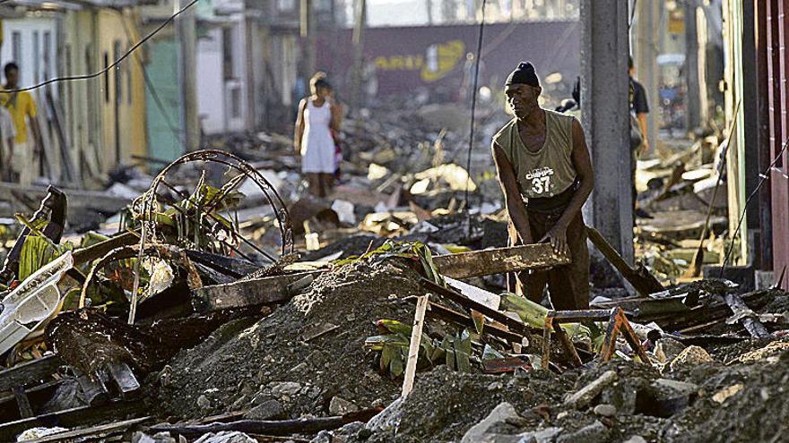 Un hombre intenta retirar los escombros ante de su casa. // Efe