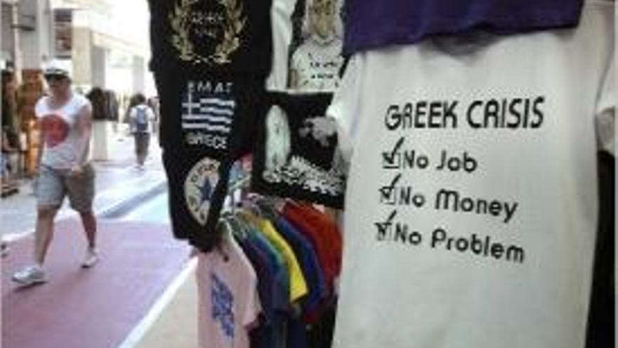 Un carrer comercial d&#039;Atenes amb una camiseta referent a la crisi.