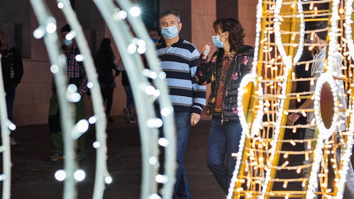 Un grupo de personas transita por una calle de Santa Cruz iluminada con las luces de Navidad.