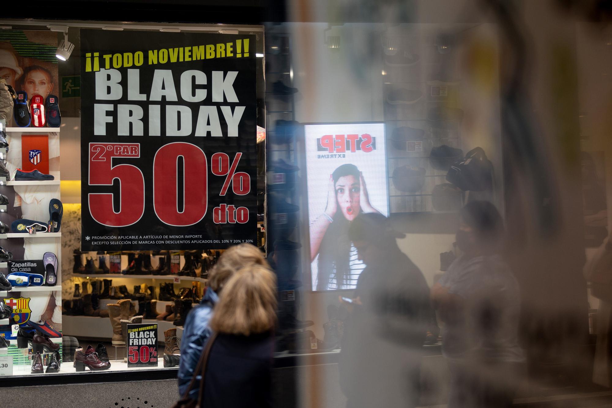 Un grupo de personas caminan frente a una tienda con ofertas por el ‘Black Friday’ en Madrid.