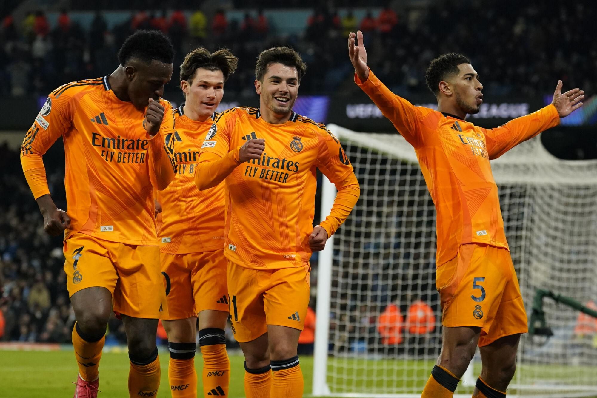 Real Madrid's Jude Bellingham, right, celebrates with teammates after scoring his sides third goal during the Champions League playoff first leg soccer match between Manchester City and Real Madrid at the Etihad Stadium in Manchester, England, Tuesday, Feb. 11, 2025. (AP Photo/Dave Thompson)