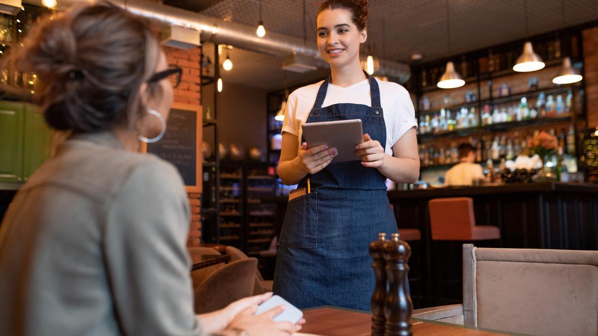 Una camarera atiende a una joven en un restaurante.