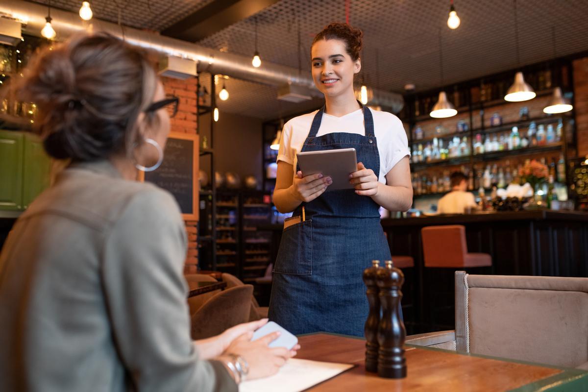 Una camarera atiende a una joven en un restaurante.