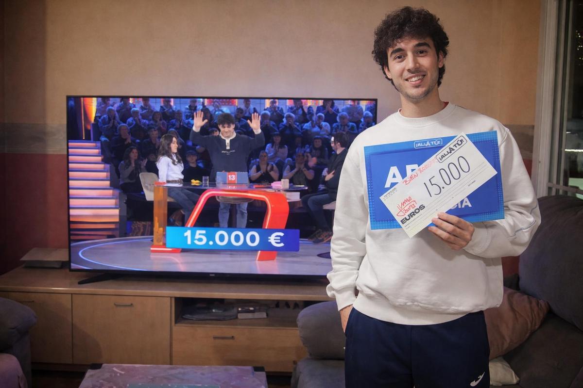 El joven Adam muestra el cheque ganado.