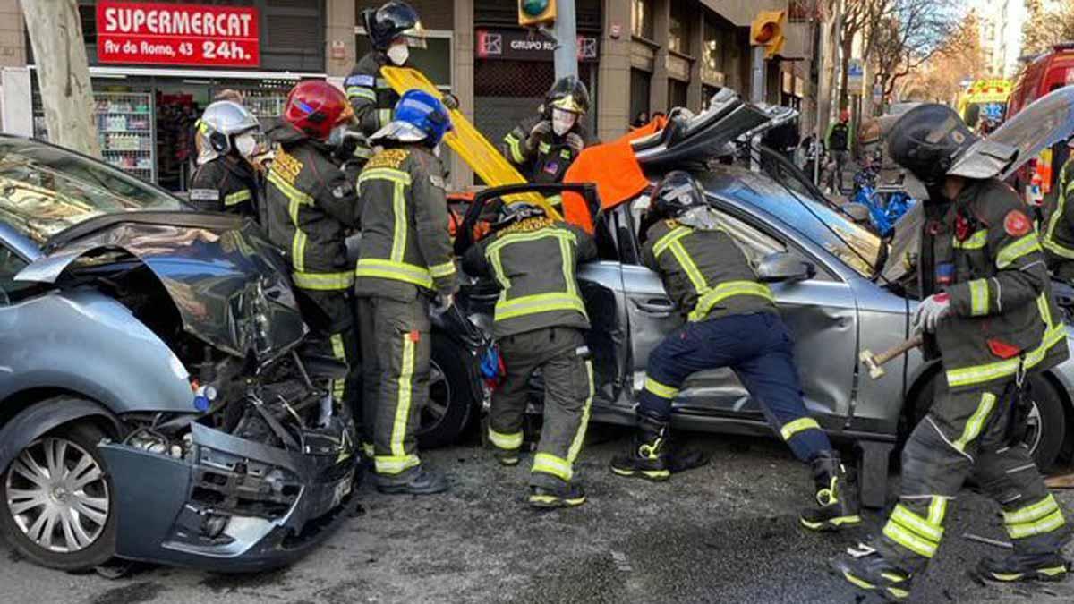 Los bomberos trabajan para liberar a una persona atrapada en su coche, tras un accidente en la calle de Entença, en Barcelona