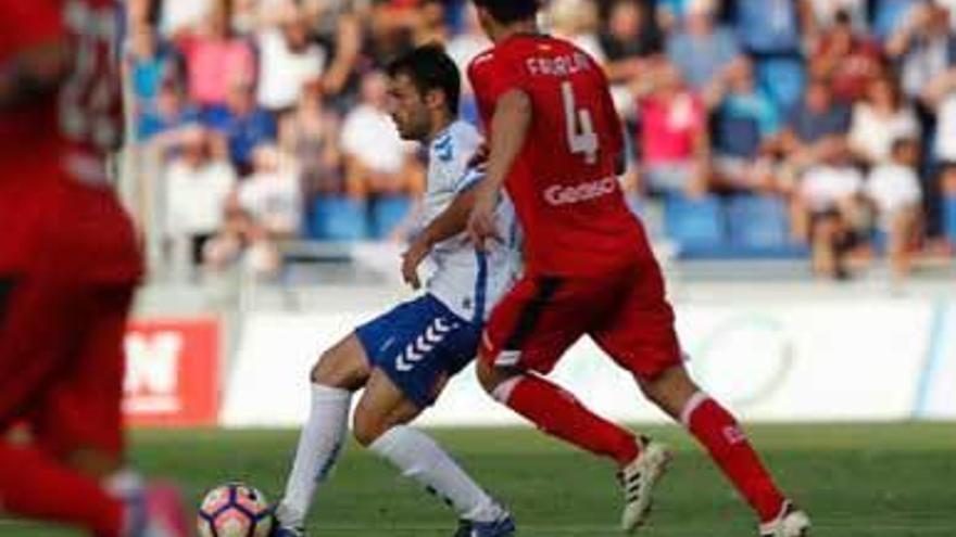 Aitor Sanz da un pase ante la presión de Faurlín.