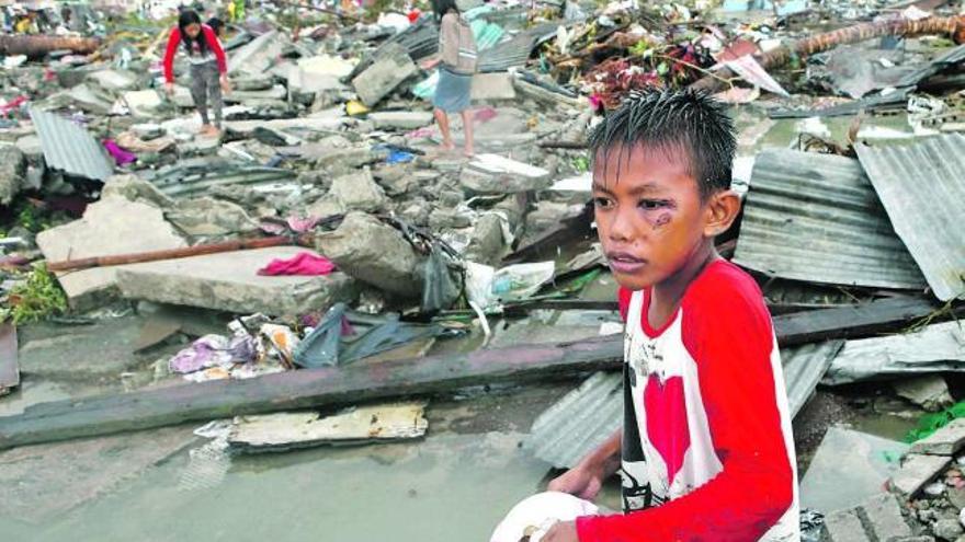 Un niño recolecta monedas entre los escombros de la ciudad de Tacloban, una de las más afectadas por la tragedia. / efe