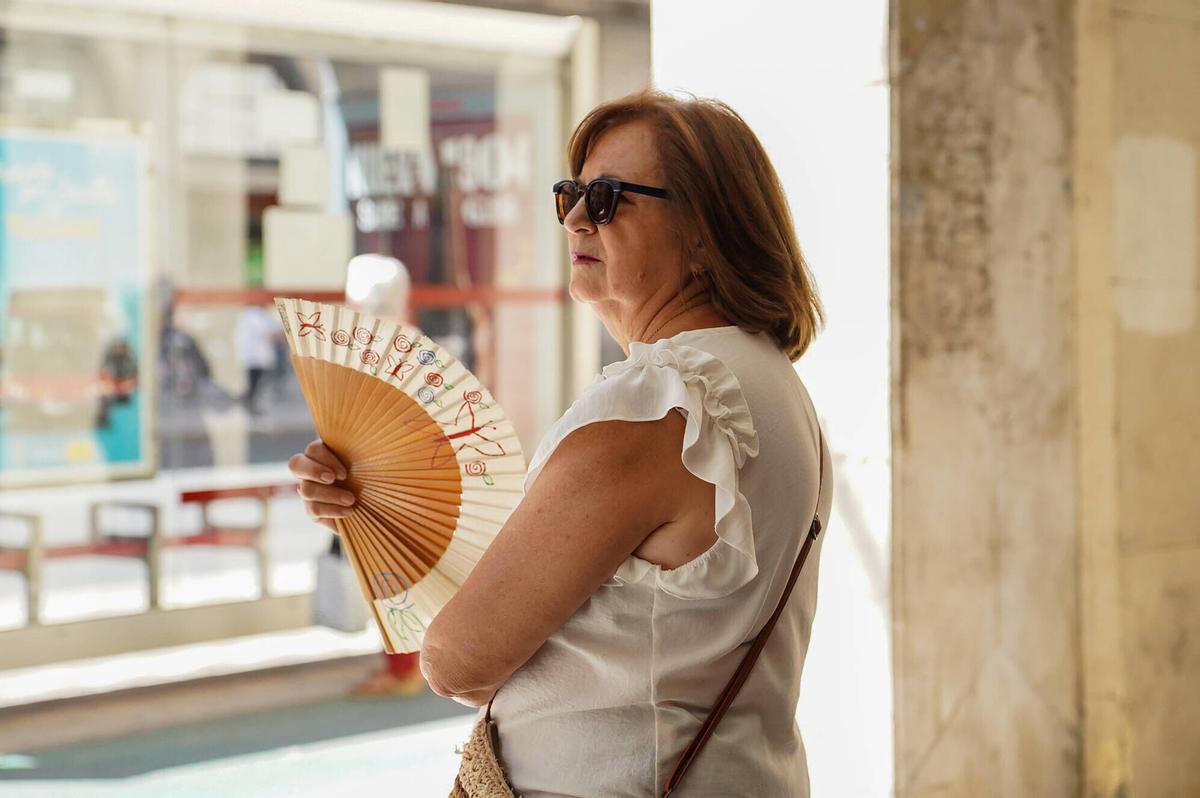 Mujer abanicándose en la sombra con un abanico para aliviar el intenso calor en Sevilla