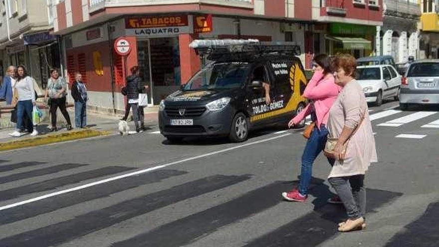 Dos mujeres cruzan en Vilagarcía, una hablando por el móvil. // N. P.