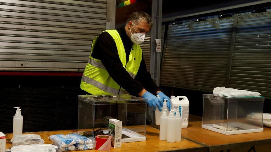 Un operario prepara una mesa en un mercado de Barcelona habilitado como colegio electoral.