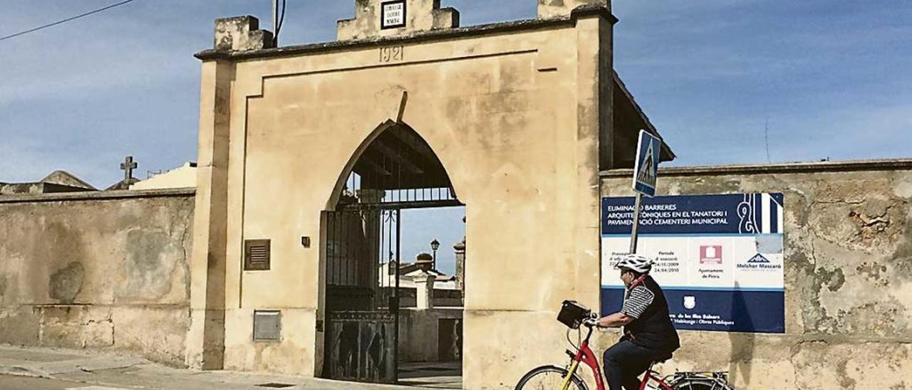 Una ciclista circulando ante el cementerio municipal de Petra.