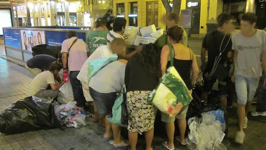 Numerosas personas buscan comida entre la basura de un supermercado.