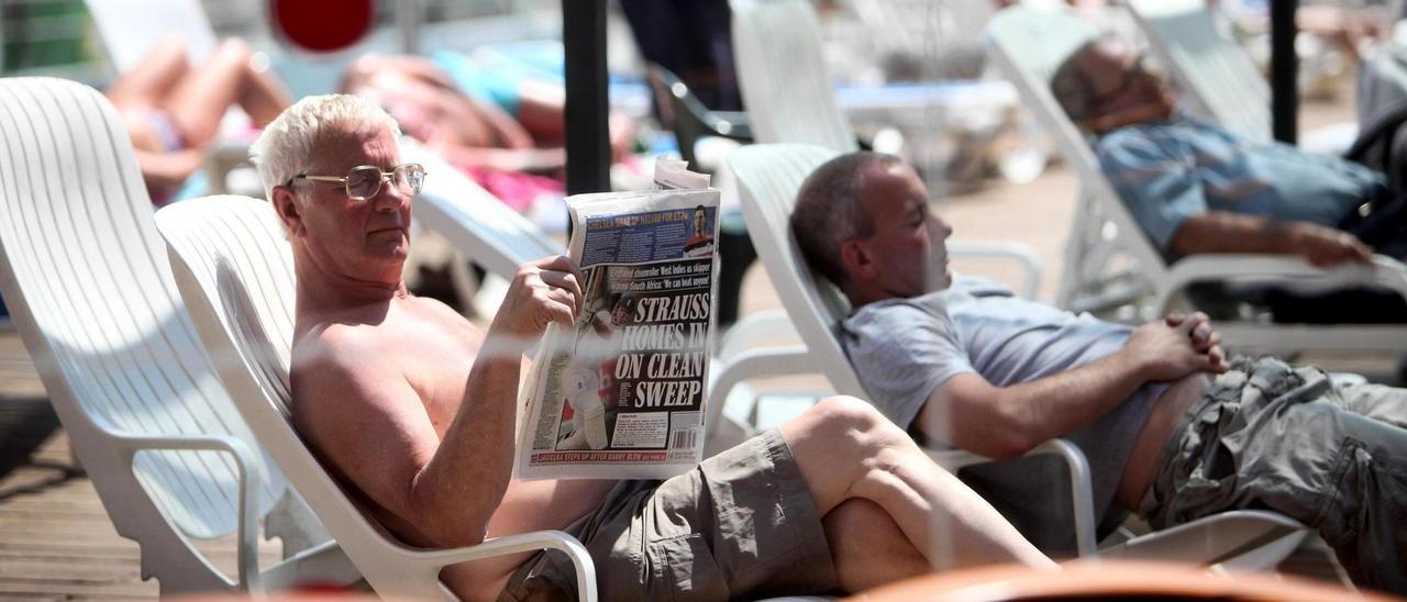 Un turista lee un periódico británico en Benidorm.