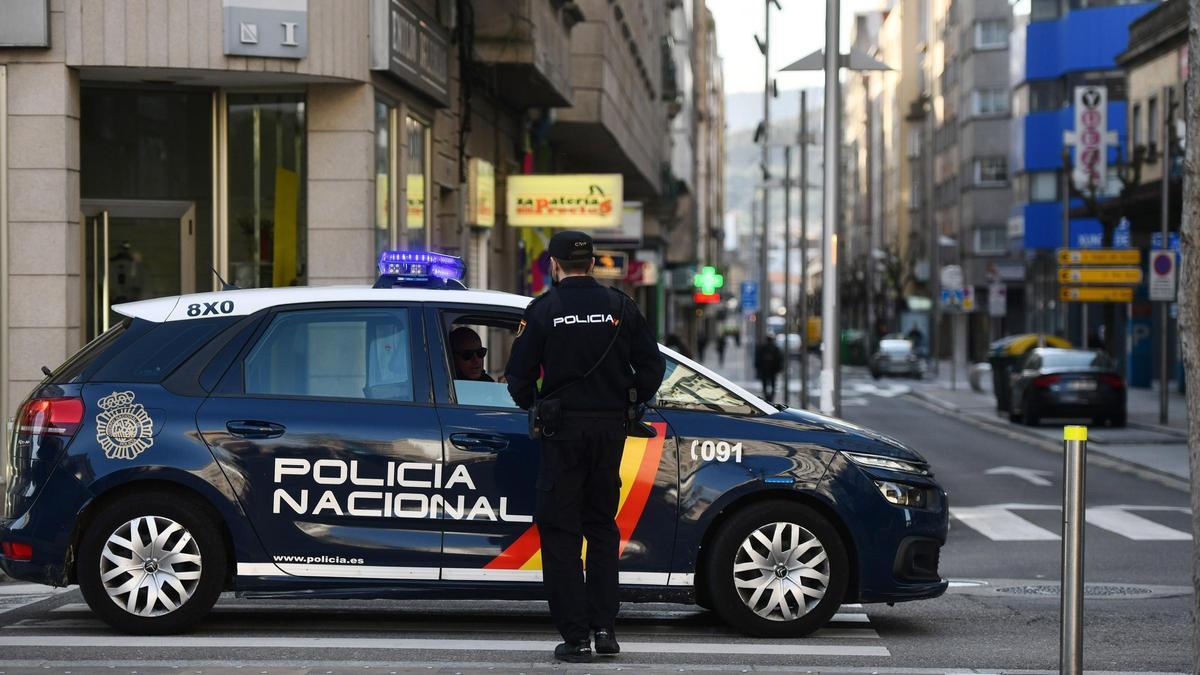 Un agente policial junto a un coche patrulla