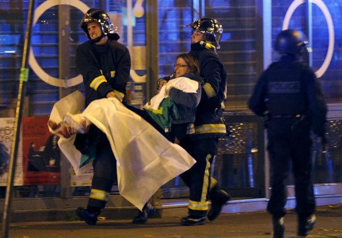 Membres de la brigada d’incendis ajuden una persona lesionada, prop de la sala de concerts Bataclan després dels trets mortals a París.