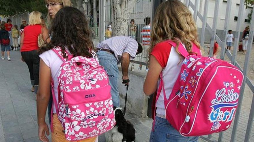 Dos niñas portan sus mochilas.