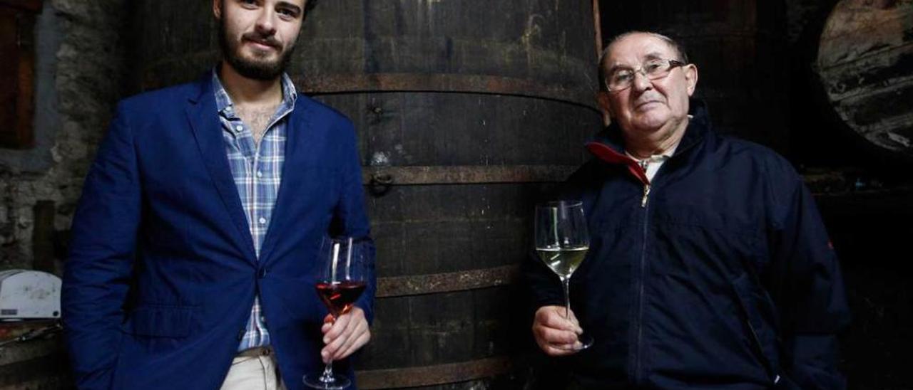 Carlos Ron, con una copa de vino rosado en la mano, y su abuelo Fernando Martínez, con vino blanco, en el llagar familiar del siglo XIV.