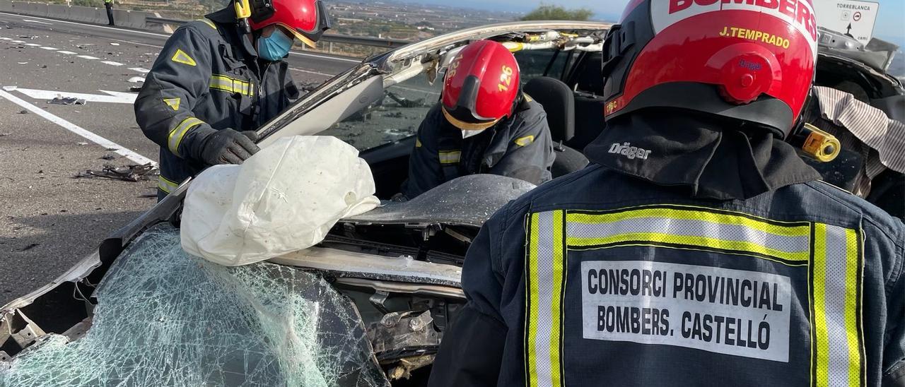 Colisión de un coche y un camión en la CV-13. Bomberos excarcelando al conductor del vehículo fallecido.