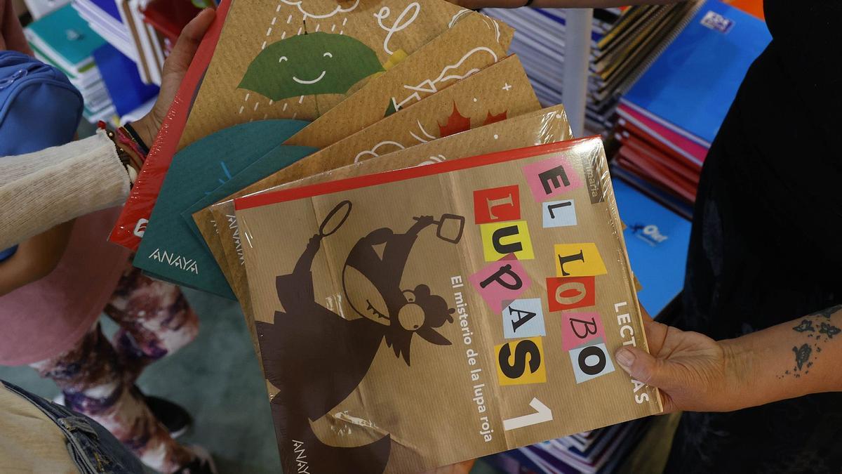 Una familia recoge sus libros de texto en la librería Cativos.