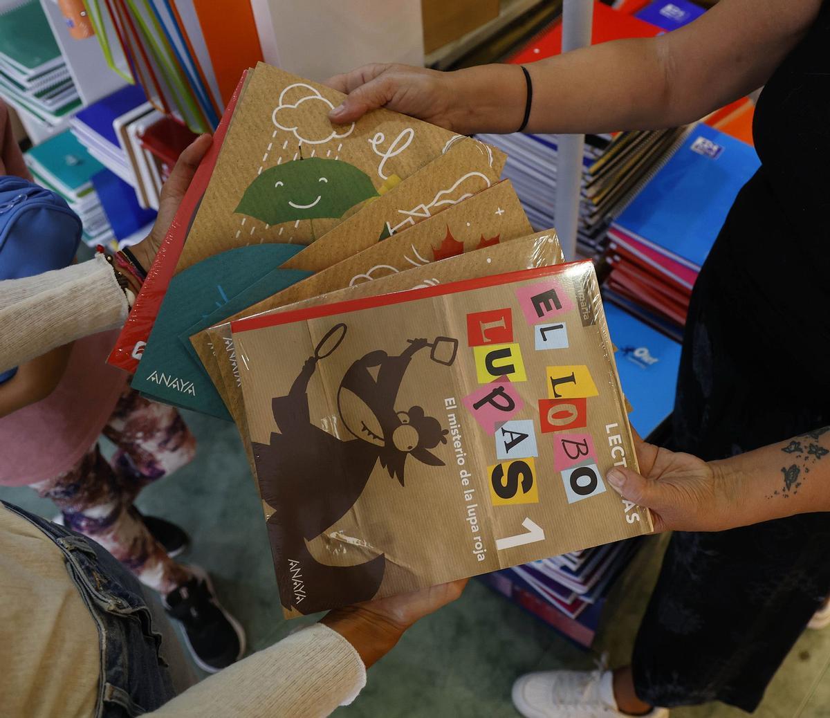 Una familia recoge sus libros de texto en la librería Cativos.