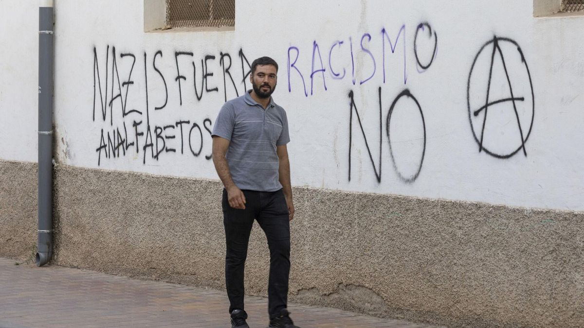 Un hombre pasa junto a una pintada contra el racismo en el barrio de San Antonio de Torre Pacheco (Murcia).